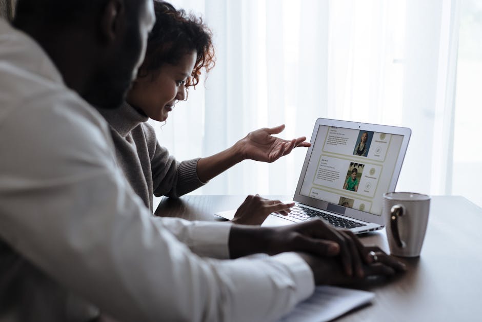 A diverse couple sitting at a table using a laptop to make important home decisions.